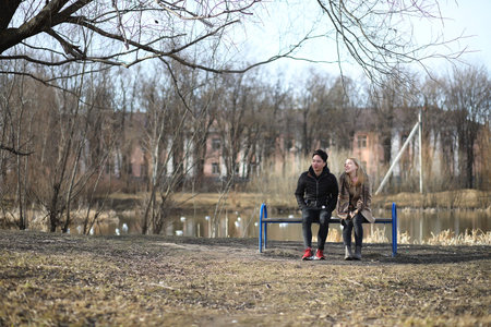 A couple of friends sitting on a bench in an autumn park