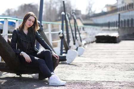 A girl sitting beside a river in the city in springの写真素材