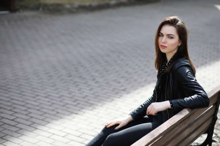 A girl sitting on a bench in the city in springの写真素材