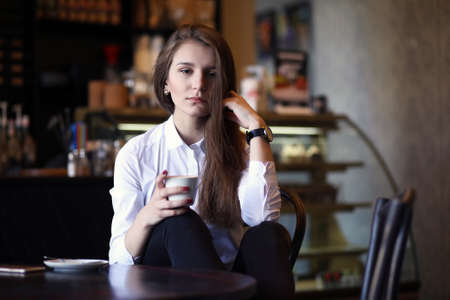 A girl in white having breakfast in a cafeの写真素材