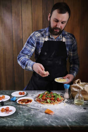 Man preparing a pizza, knead the dough and puts ingredientsの写真素材