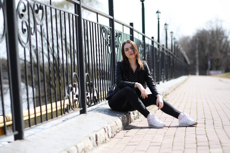 A girl sitting by the river in the city in springの写真素材