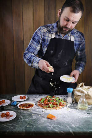 A man preparing a pizza, kneading the dough and putting ingredientsの写真素材