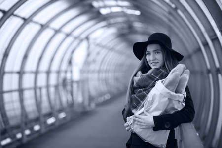 A young lady holding a bag of baguettes in an architectural tunnel in the cityの写真素材