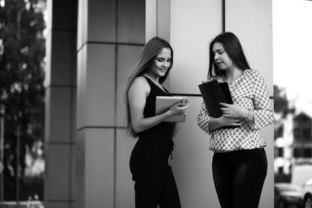 Black and white photo of two ladies in business attire looking at a computer tabletの写真素材