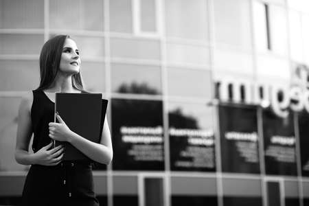 A black and white photo of a lady in business attire holding filesの写真素材
