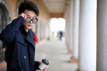 Asian young man in a coat on the streetの写真素材