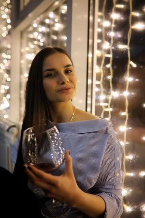A girl in an evening dress holding a glass of wine sitting in a cafe