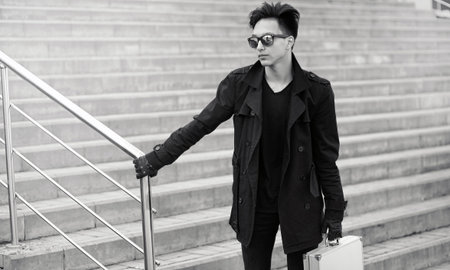 An Asian man wearing sunglasses with a metal suitcase in the city.の写真素材