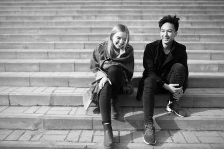 A young couple sitting on the stairs in a parkの写真素材