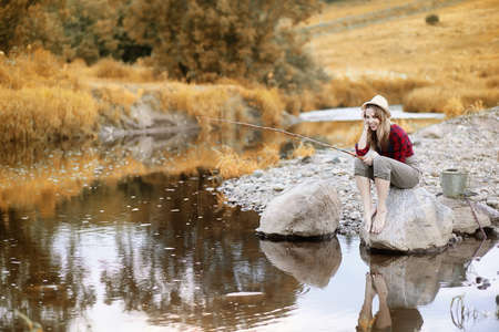 Girl in autumn with a fishing rodの写真素材