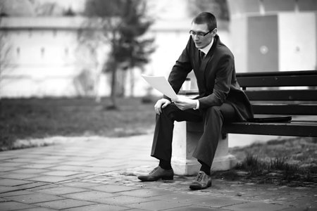 A businessman in a suit sitting on the bench in the streetの写真素材
