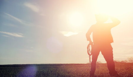 A man cowboy hat and a loso in the field. American farmer in a fの写真素材
