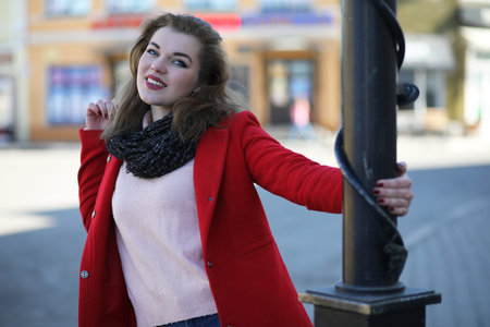 Pretty girl on a walk in red coat in the city