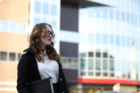 Business lady in strict clothes on the background of buildingsの写真素材