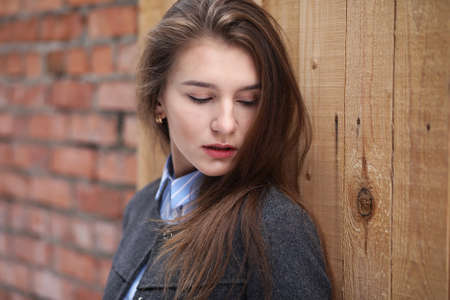 Young beautiful girl near red brick wall posingの写真素材