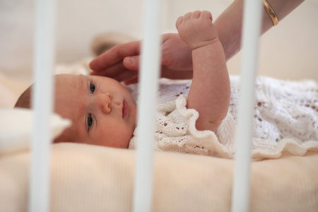 Newborn cute baby lies in the crib and looking motherの写真素材