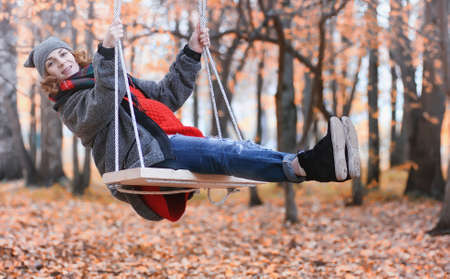 Girl in autumn city park in leaf fall. Young beautiful mother wiの写真素材