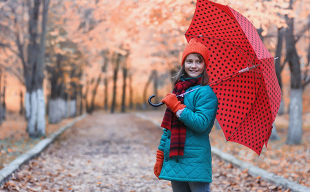 Girl in autumn city park in leaf fall. Young beautiful mother wiの写真素材