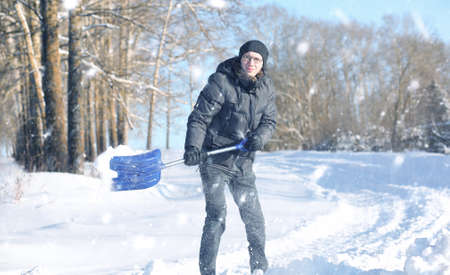 man remove snow with shovel from the road in snowy winterの写真素材