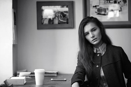 Girl with coffee. Young beautiful girl is sitting in a cafe and