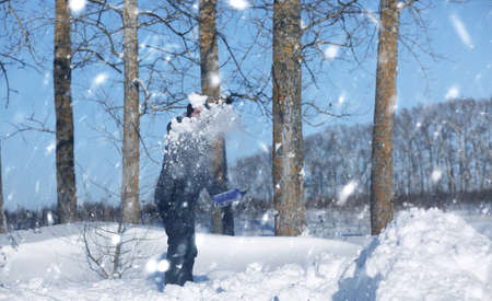 man remove snow with shovel from the road in snowy winterの写真素材