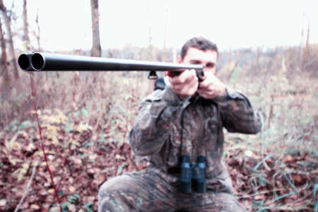A man in camouflage and with a hunting rifle in a forest on a spの写真素材