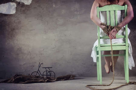 Young girl tied up on the floor. The abducted girl. The victim of violence sits on floor with tied hands. Domestic violence.の写真素材