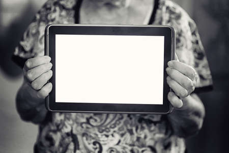 elder woman holding in a hands tablet with empty screenの写真素材