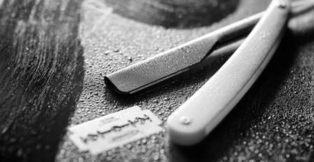 A dangerous razor and a metal blade on the table. Men's shaving accessories. Brutal shaver for real men. Drops of water on table.
の写真素材