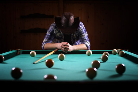 A man with a beard plays a big billiard. Party in 12-foot pool. Billiards in the club game for men. A man with a cue breaks the pyramid.の写真素材