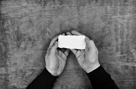 monochrome photo male hands holding a white blank sheet of paperの写真素材