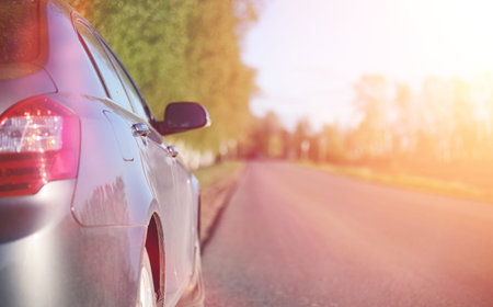 The car is on the road. Summer road on which there is a parked c