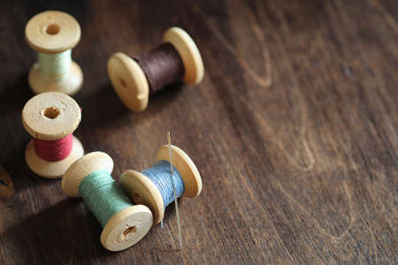 Sewing thread on a wooden background. Set of threads on bobbinsの写真素材