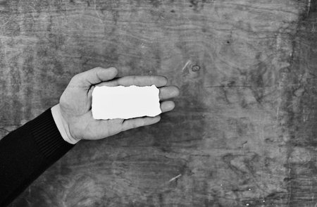 monochrome photo male hands holding a white blank sheet of paper