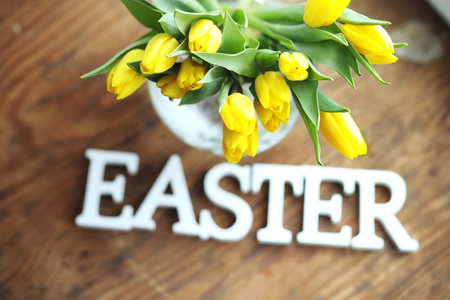 A bouquet of yellow tulips in a vase on the floor. A gift to a w