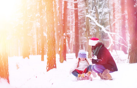 A winter fairy tale, a young mother and her daughter ride a sled