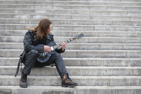 Rock guitarist on the steps. A musician with a bass guitar on a steps
