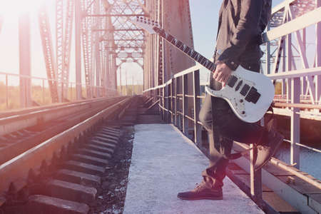 A man with an electric guitar on the railway. A musician in a leの写真素材