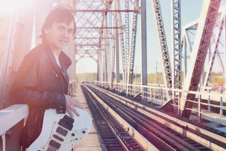 A man with an electric guitar on the railway. A musician in a leの写真素材