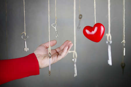 hand stretching for one of the many old vintage keys hanging on threadsの写真素材