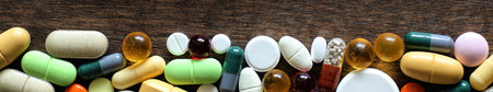 Medical background of various colorful medications on a textured wooden