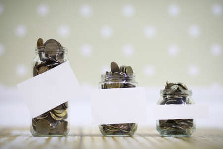 Accumulated coins stacked in glass jars on the floorの写真素材