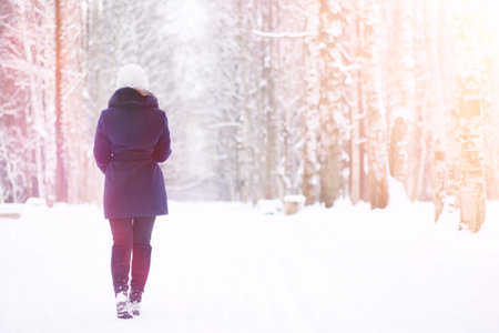 A young girl in a winter park on a walk. Christmas holidays in the winter forest. Girl enjoys winter...