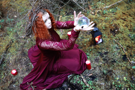 The red-haired witch holds a ritual with a crystal ball