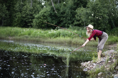 Girl by the river with a fishing rod