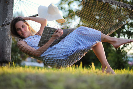 Beautiful young girl lying and reading a bookの写真素材