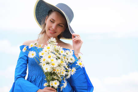 Young cute girl in a hat in a field at sunsetの写真素材