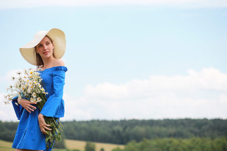 Young cute girl in a hat in a field at sunsetの写真素材