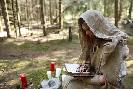 A man in a cassock spends a ritual in a dark forestの写真素材